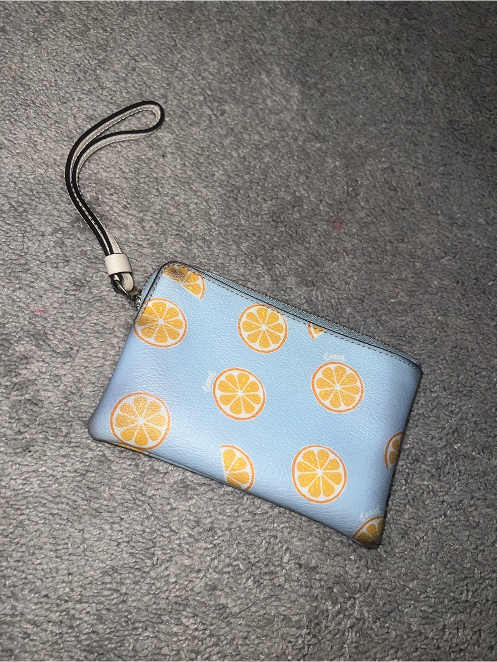 light blue Coach corner zip wristlet featuring orange print